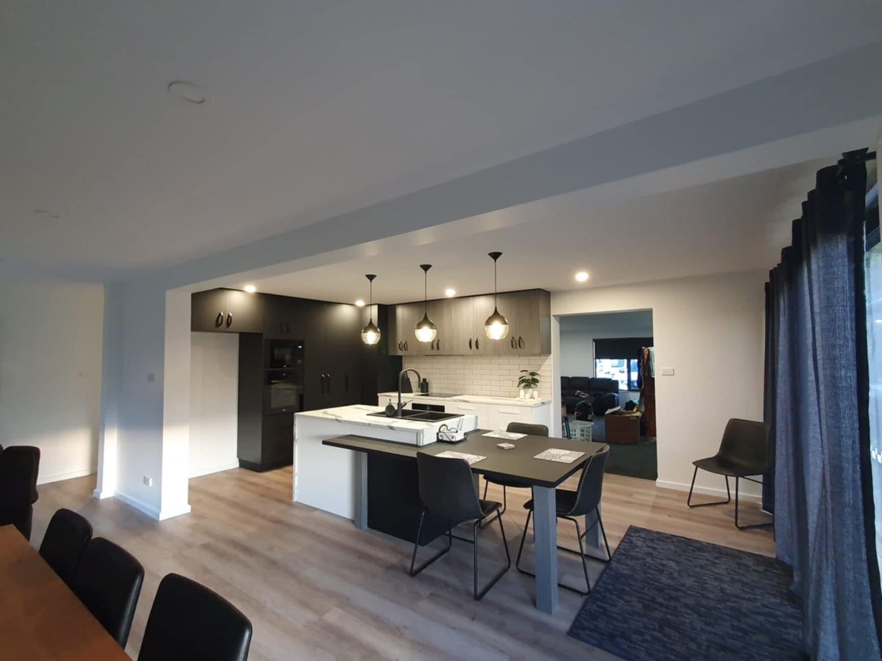 Open-plan kitchen in dark and woodgrain cabinetry, built by Central Coast Joinery