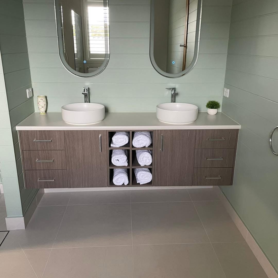 Floating double vanity in woodgrain with twin basins, a stone top and open towel shelving, built by Central Coast Joinery